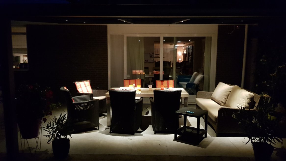 Espace extérieur cozy avec canapés, tables et éclairage douce, idéal pour des soirées relaxantes.