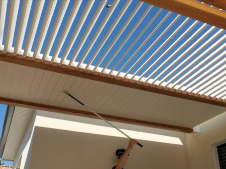 Pergola moderne en bois avec lames orientables sous un ciel bleu, apportant ombre et style à un espace extérieur.