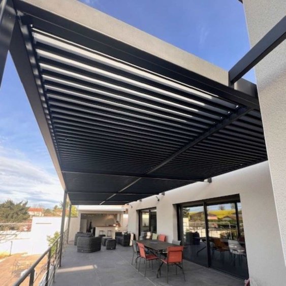 Terrasse moderne avec pergola en aluminium noir, mobilier extérieur et vue dégagée sous un ciel bleu. Idéal pour se détendre.